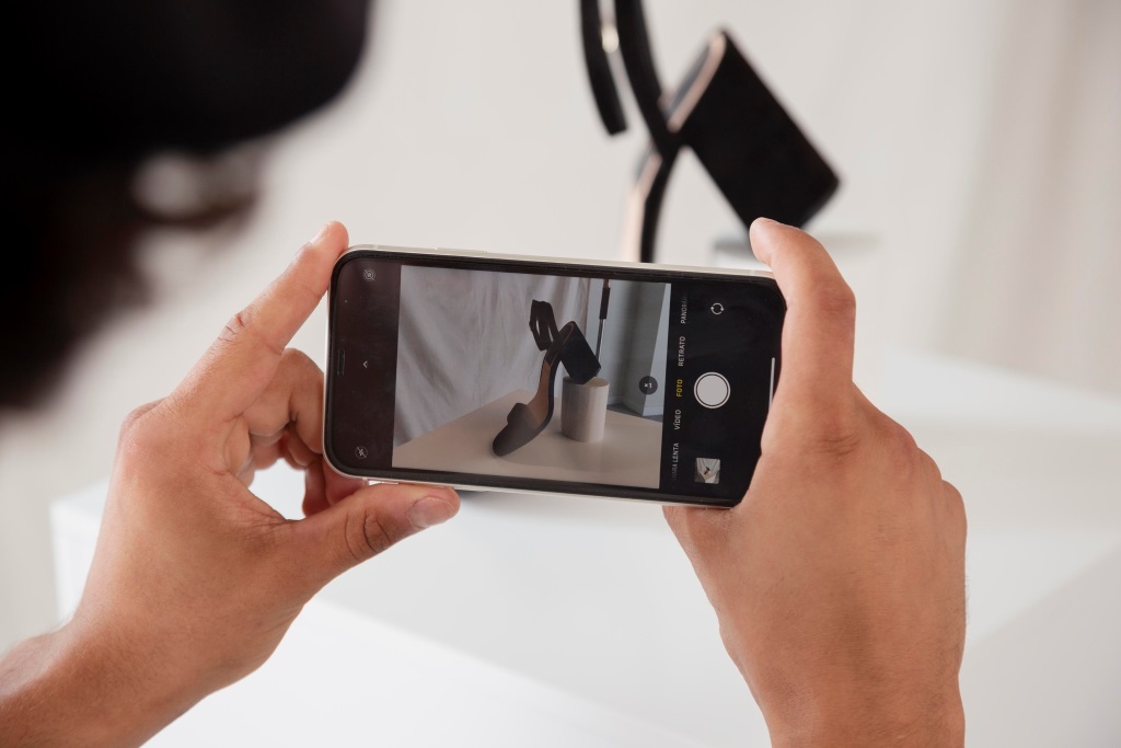 Hände halten Smartphone für Fotoshooting von Schuh