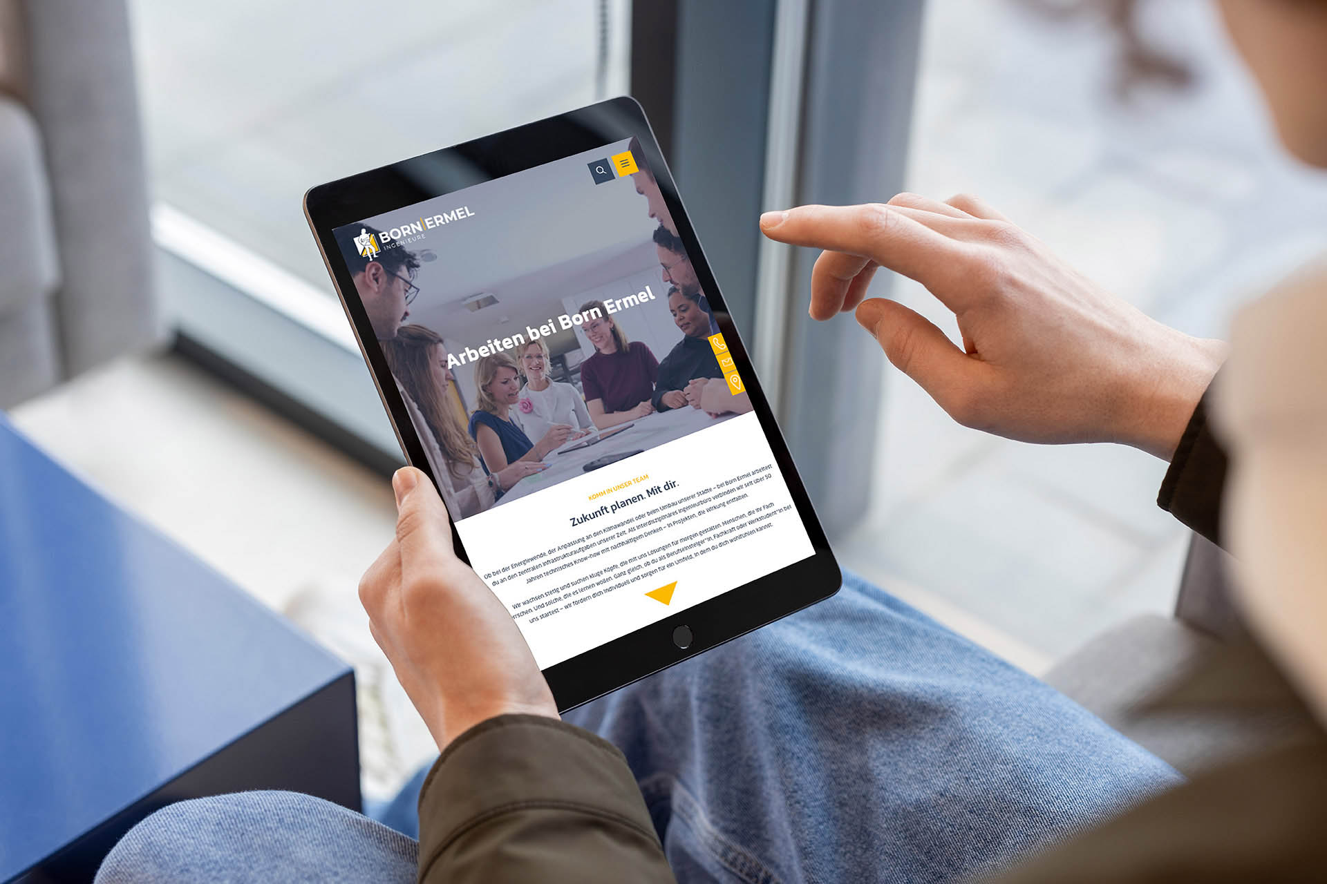 Tablet mit geöffneter Karriereseite von Born Ermel auf dem Schoß einer sitzenden Person, Finger tippt auf den Bildschirm