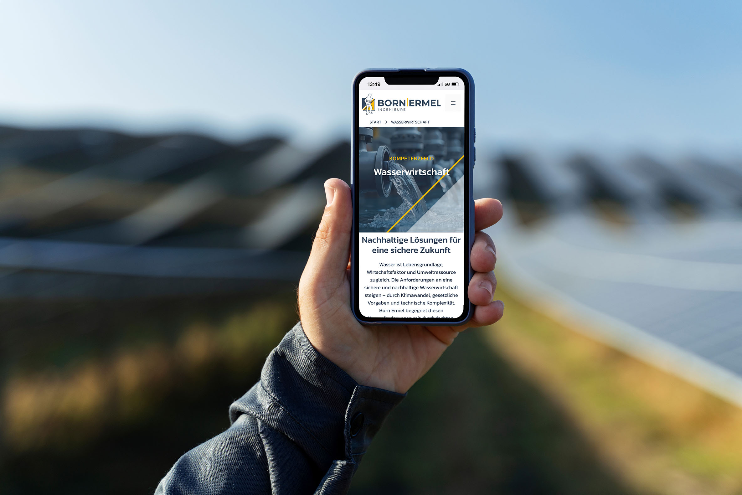 Smartphone mit geöffneter Born-Ermel-Website, Fokus auf das Kompetenzfeld Wasserwirtschaft, im Hintergrund eine Solaranlage
