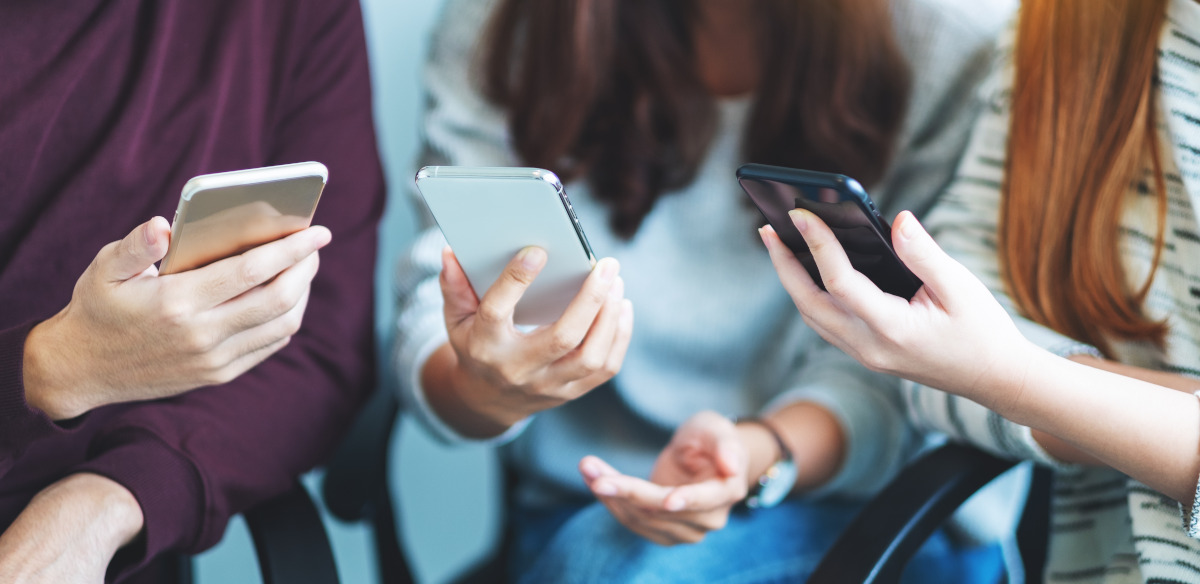 Drei junge Menschen, die ihre Smartphones in den Händen halten